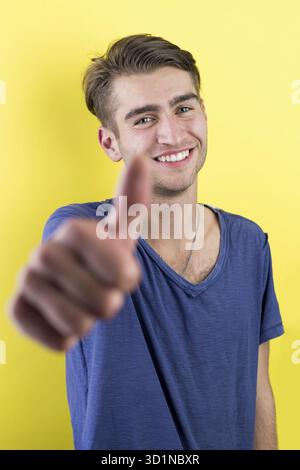 Smiling young man casual dressed standing against yellow background Stock Photo