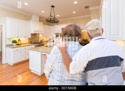 Senior Couple Looking Over Beautiful Custom Kitchen Stock Photo