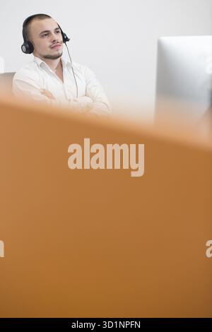 Smiling casual young man with headset using computer in a bright office Stock Photo
