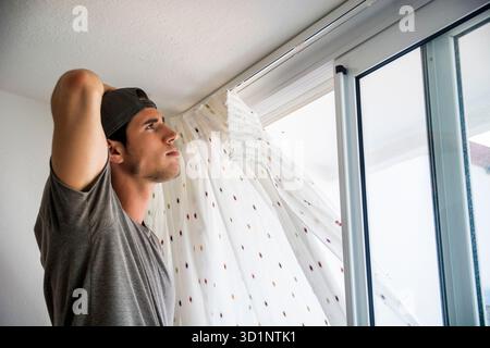 Young man installing curtains over window Stock Photo