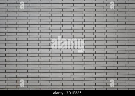 A straight-on, symmetrical photograph of a modern white brick wall. The neat running bond pattern and contrasting dark gray or black grout. Stock Photo