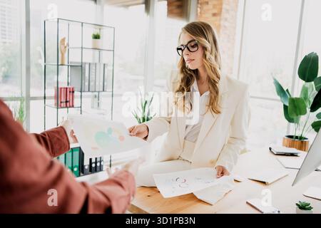 Young professional businesswoman in a stylish white suit working in a modern office, reviewing documents for a presentation Stock Photo