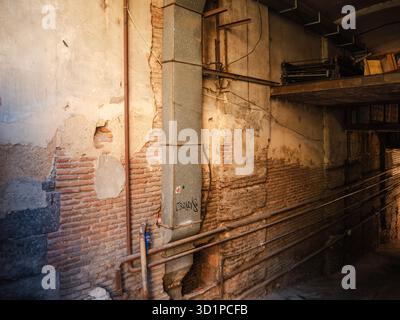 Old Tbilisi passage with exposed brick, peeling plaster, pipes and deep shadows under warm afternoon light. Stock Photo