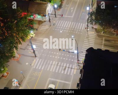 Aerial view of a quiet city street illuminated by streetlights at night ...