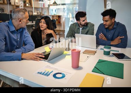 Team meeting in modern office with coworkers discussing project ideas Stock Photo