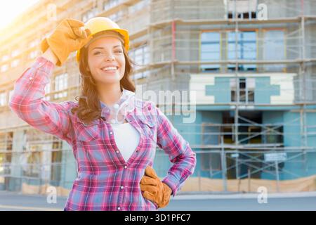 Portrait of Young Female Construction Worker Wearing Gloves, Hard Hat and Protective Goggles at Construction Site. Stock Photo
