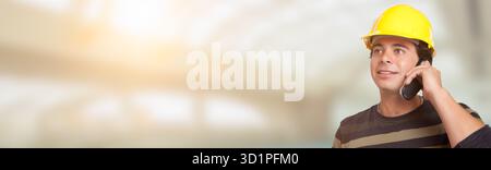 Handsome Adult Hispanic Male Contractor in Hard Hat Using Cell Phone Wide Banner with Room For Text. Stock Photo