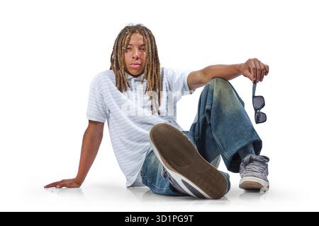 Young man wearing dreadlocks and casual clothing posing relaxed on white background Stock Photo