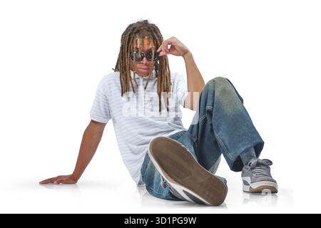 Young man with dreadlocks modeling sunglasses, sitting casually on white background Stock Photo