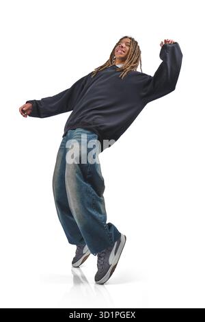 Young man with dreadlocks dancing in hip hop attire, making a stop gesture with a smile Stock Photo