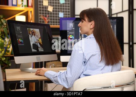 Professional retoucher editing photo on computer at table in office Stock Photo
