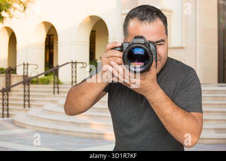 Hispanic Young Male Photographer With DSLR Camera Outdoors Stock Photo