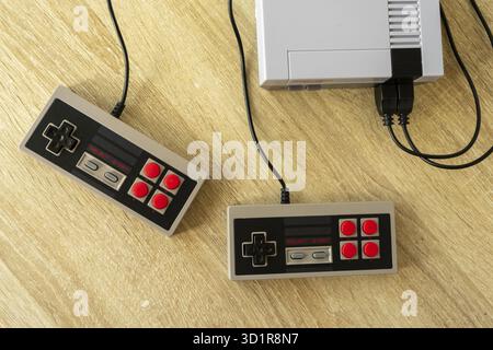 Retro gaming console with classic gamepad controller on a wooden table Stock Photo