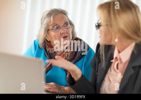 Woman Helping Senior Adult Lady on Laptop Computer Stock Photo