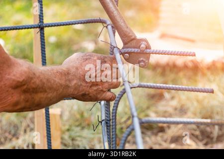 Worker Using Tools To Bend Steel Rebar At Construction Site Stock Photo