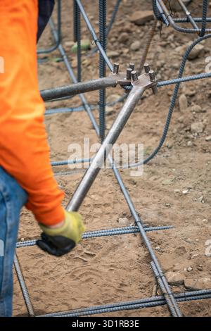 Worker Using Tools To Bend Steel Rebar At Construction Site Stock Photo