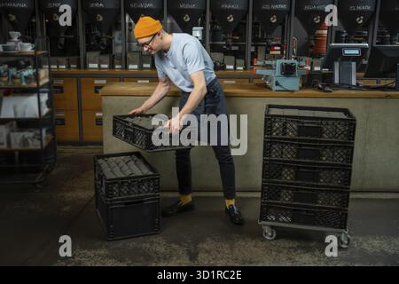 Male worker or business owner uploads packages of coffee on factory or warehouse, barista in coffee shop Stock Photo