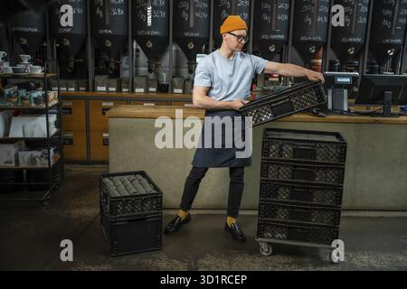 Male worker or business owner uploads packages of coffee on factory or warehouse, barista in coffee shop Stock Photo