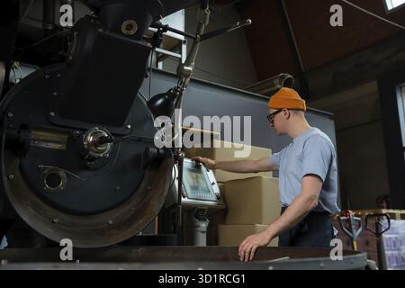 Modern coffee roasting factory man worker operating process of creating coffee Stock Photo