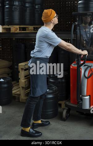 Hipster man in hat and apron roasting factory worker preparing coffee beans for coffee brewing Stock Photo