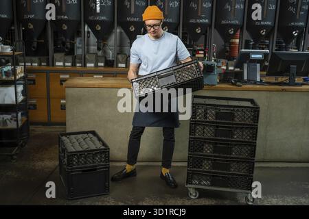 Male worker or business owner uploads packages of coffee on factory or warehouse, barista in coffee shop Stock Photo