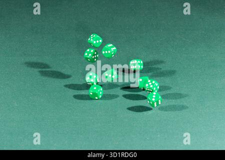 Ten green dices falling on a green table Stock Photo