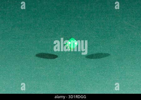 One green dice falling on a green table Stock Photo
