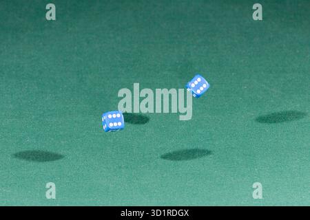 Two blue dices falling on a green table Stock Photo