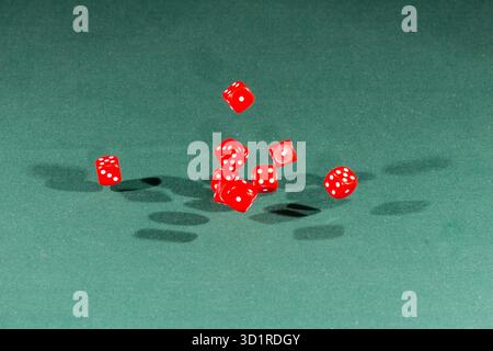 Ten red dices falling on a green table Stock Photo