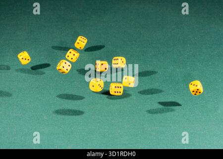 Ten yellow dices falling on a green table Stock Photo