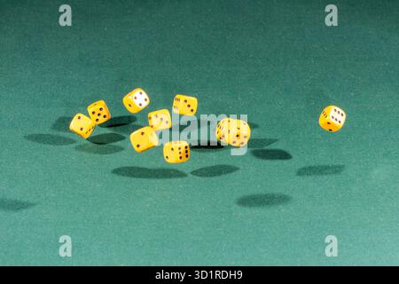 Ten yellow dices falling on a green table Stock Photo