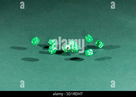 Ten green dices falling on a green table Stock Photo