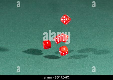 Five red dices falling on a green table Stock Photo