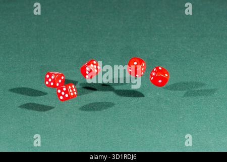 Five red dices falling on a green table Stock Photo