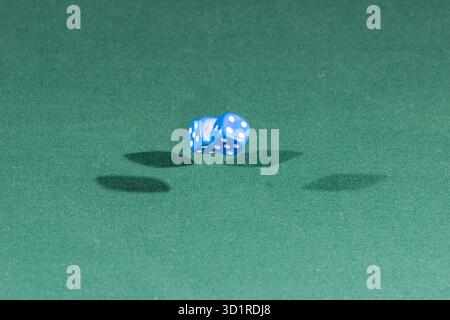 Two blue dices falling on a green table Stock Photo
