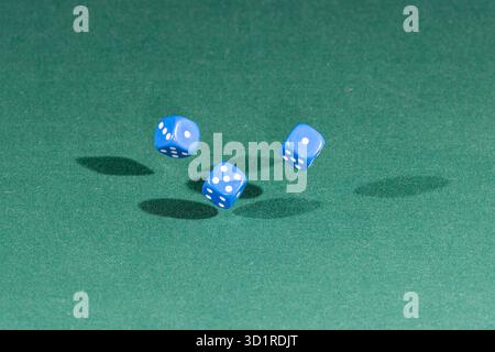 Three red dices falling on a green table Stock Photo