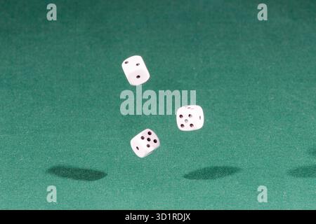 Three white dices falling on a green table Stock Photo