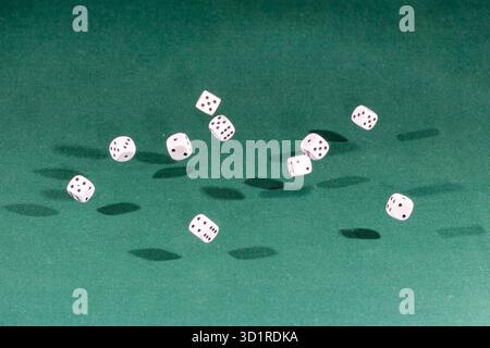Ten white dices falling on a green table Stock Photo