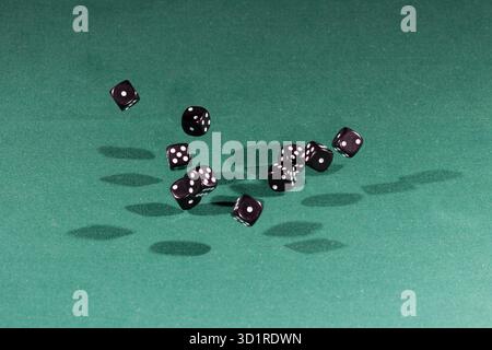Ten black dices falling on a green table Stock Photo