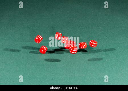 Ten red dices falling on a green table Stock Photo
