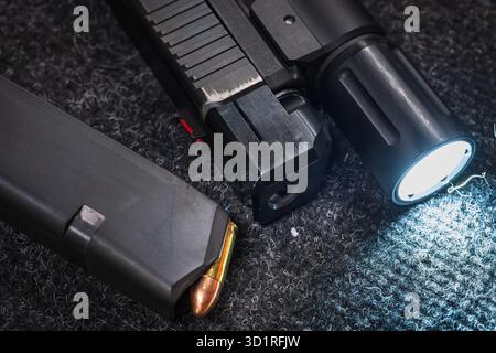 Close-up of a customized 9mm pistol featuring a muzzle brake, tactical weapon light, and a loaded magazine. Stock Photo