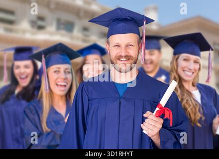 Proud Male Graduate in Cap and Gown In Front of Other Graduates Stock Photo