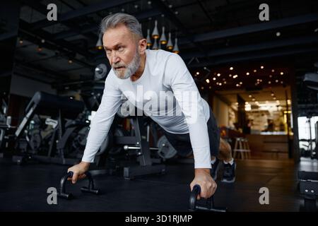 Mature man is doing push-ups in a modern gym Stock Photo