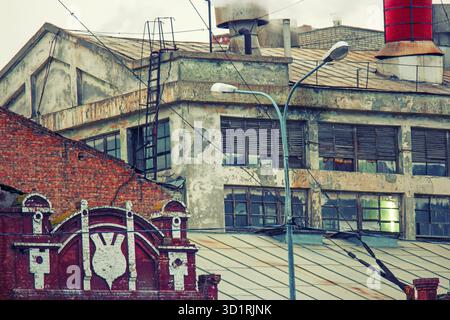 Old power plant buiding with steam from chimney on the roof toned image. Colorized shot old film color imitation Stock Photo