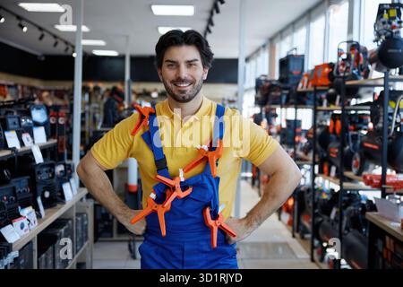 A man in overalls holds clamps on his shoulder in a store Stock Photo