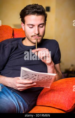 Young man sitting doing a crossword puzzle Stock Photo