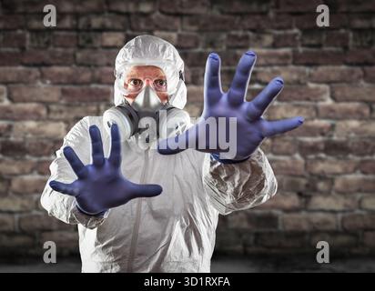 Man Wearing Hazmat Suit, Protective Gas Mask and Goggles Reaching To Stop with Hands Stock Photo