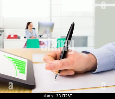 closeup of a businesswoman working with tablet and analyzing chart on the desk at the office with coworkers at the bacground Stock Photo