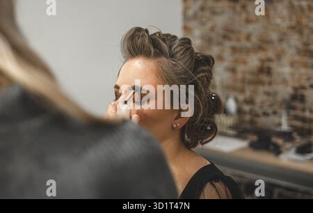 Beauty treatment process  cosmetologist applying skincare cream with a brush on young brunette model Stock Photo