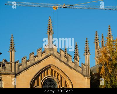 Giant crane looming over the spires of All Souls College.   All Souls College was founded by Henry VI of England and the Archbishop of Canterbury, in 1438.  Here we its ornate spires, viewed from New College Lane. The 21st century makes an appearance with a giant crane from a nearby construction site. Stock Photo